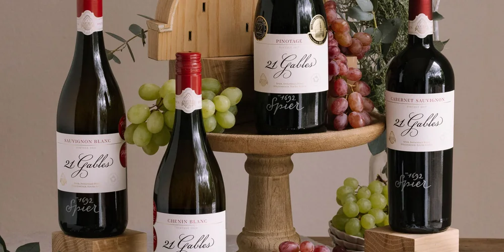 Bottles of Spier 21 Gables beside grapes on a wooden cake stand